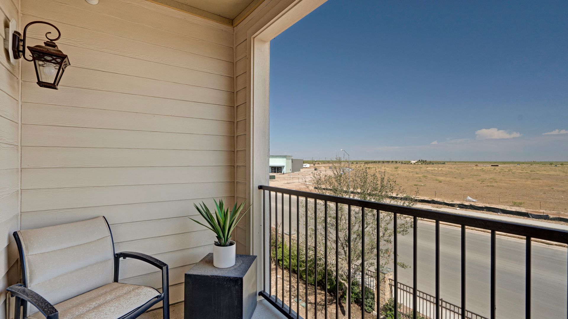 There is a balcony with a chair and a plant on it.