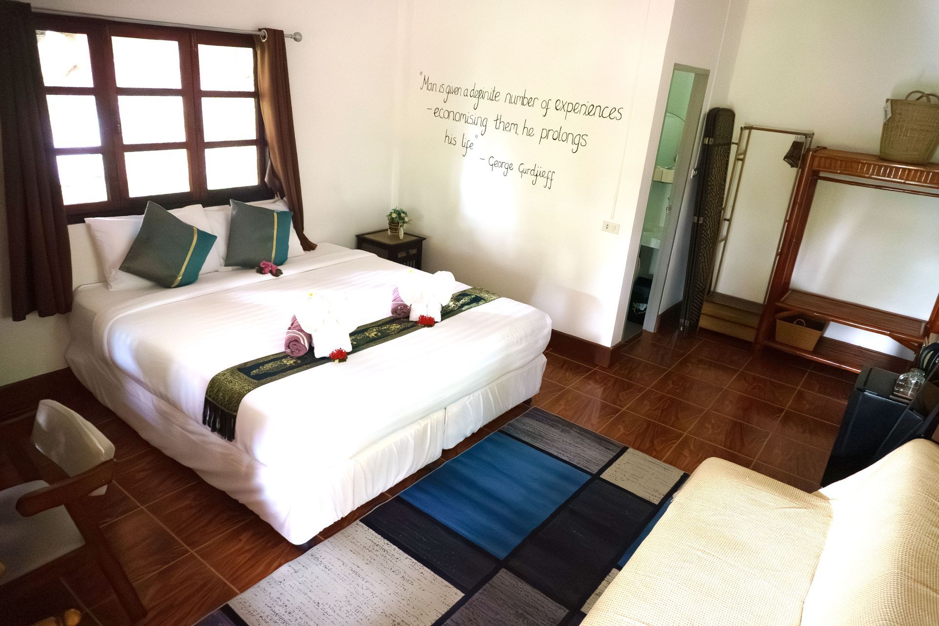 Bedroom with a large bed, brown wood floors, window, rug, and decorative pillows.