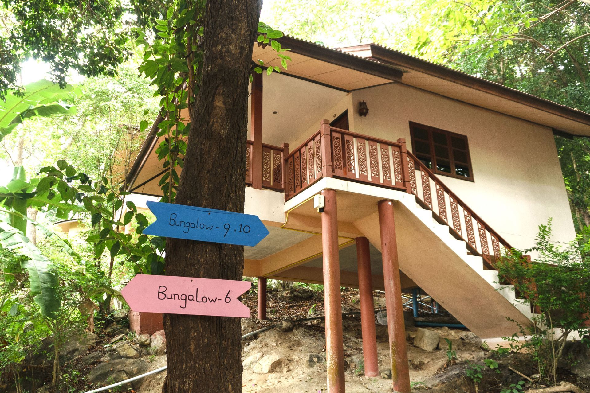 Bungalow on stilts in a tropical setting with signs pointing to bungalows.
