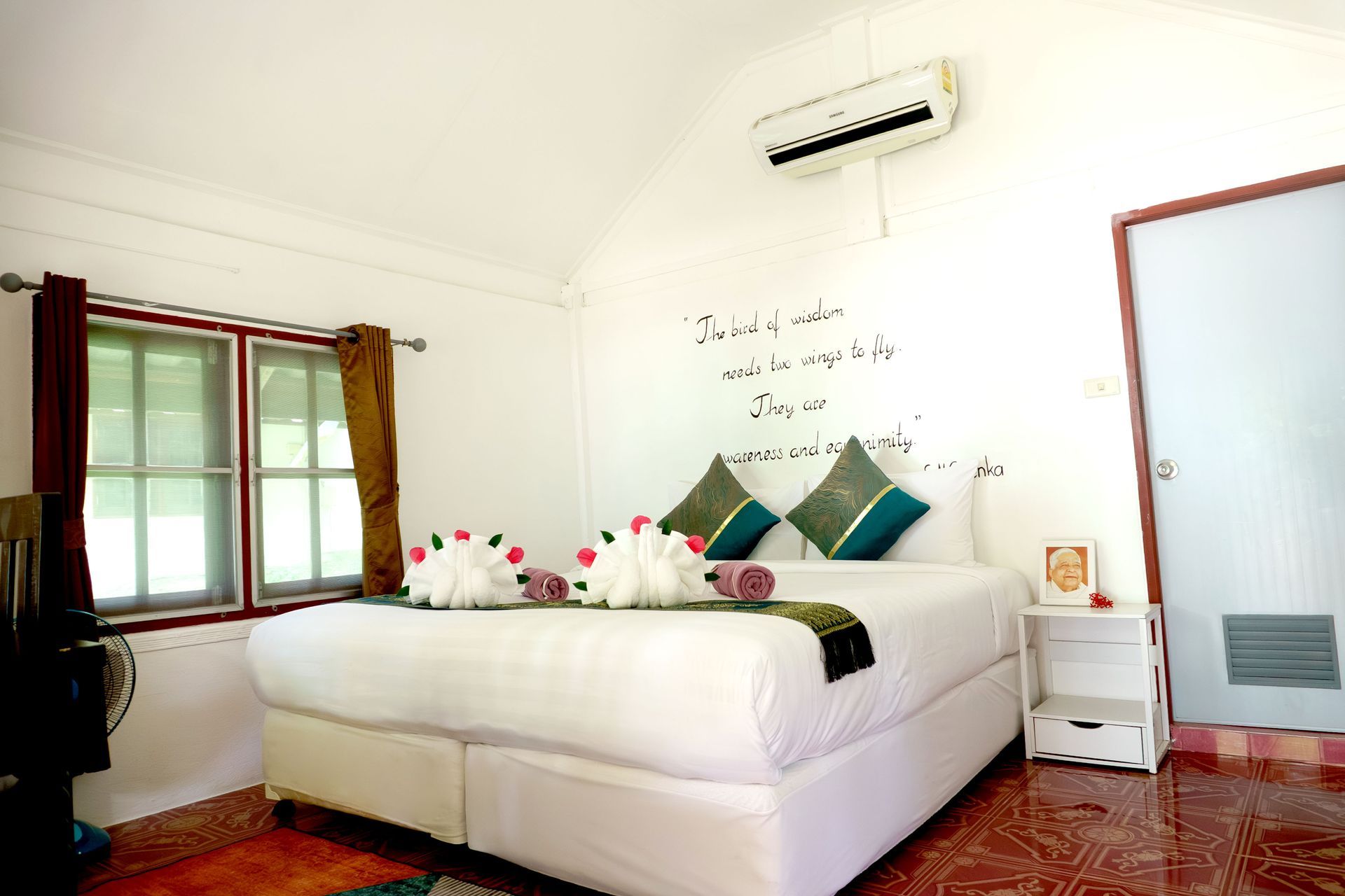 Bedroom with white walls, a bed with decorative towels, a window, and air conditioner.