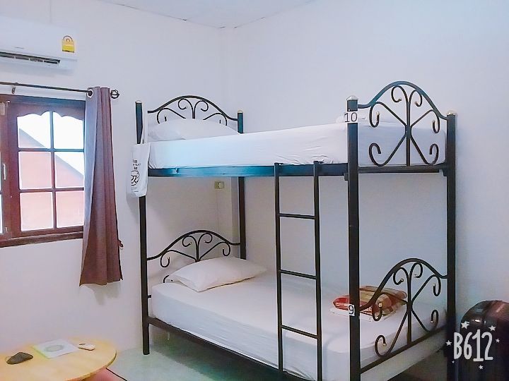 Bunk beds in a room, with a window and small table. The beds are metal, white linens.