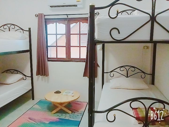 Bunk beds in a bright room with a small round table, window, and colorful rug.