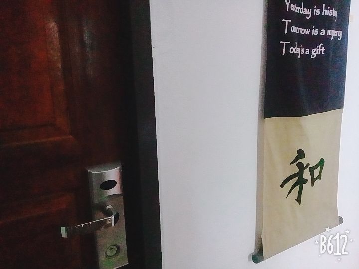 A brown door with a silver handle next to a white wall with a scroll