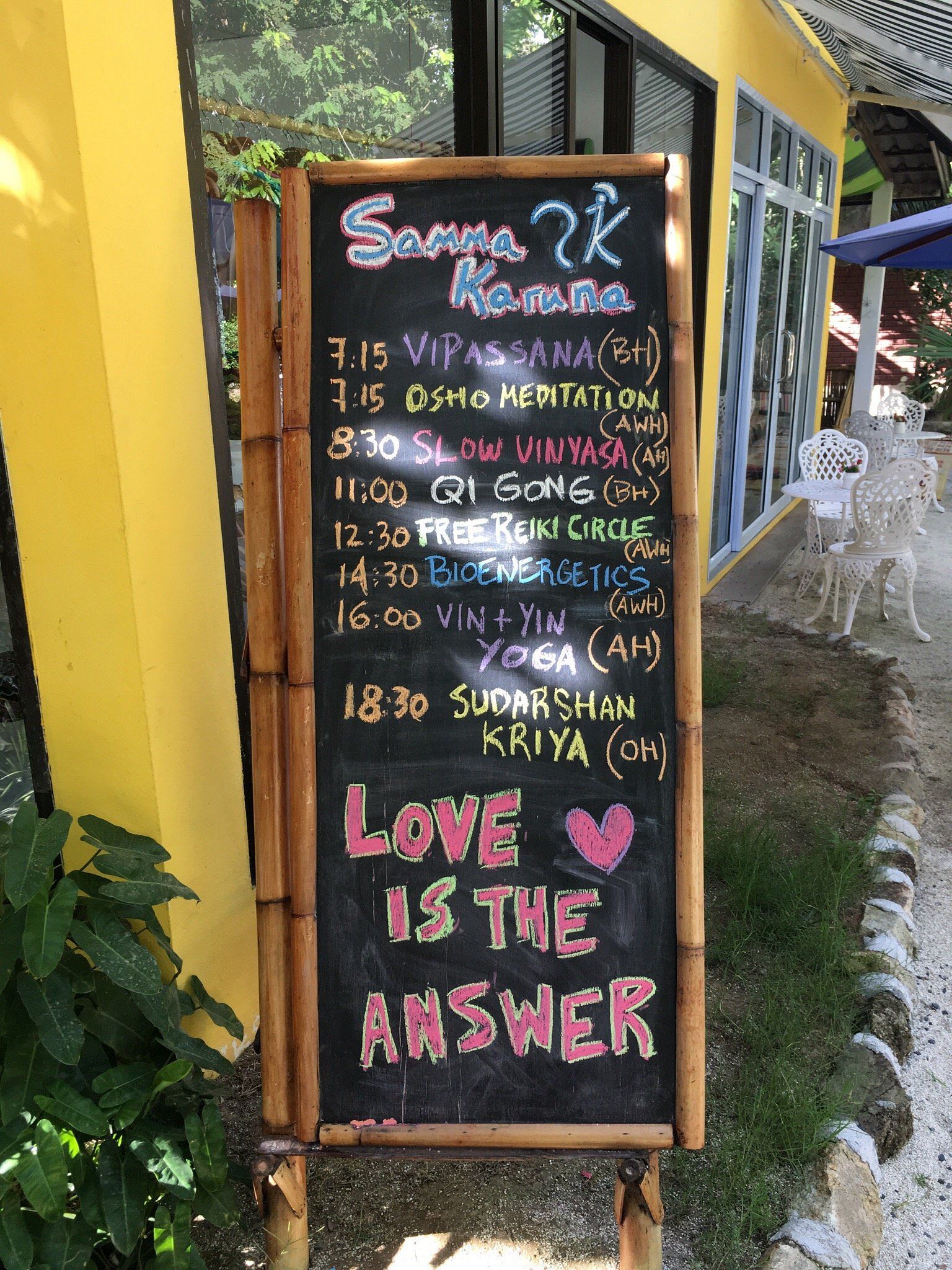 Black chalkboard sign with a daily schedule of yoga classes and the phrase 