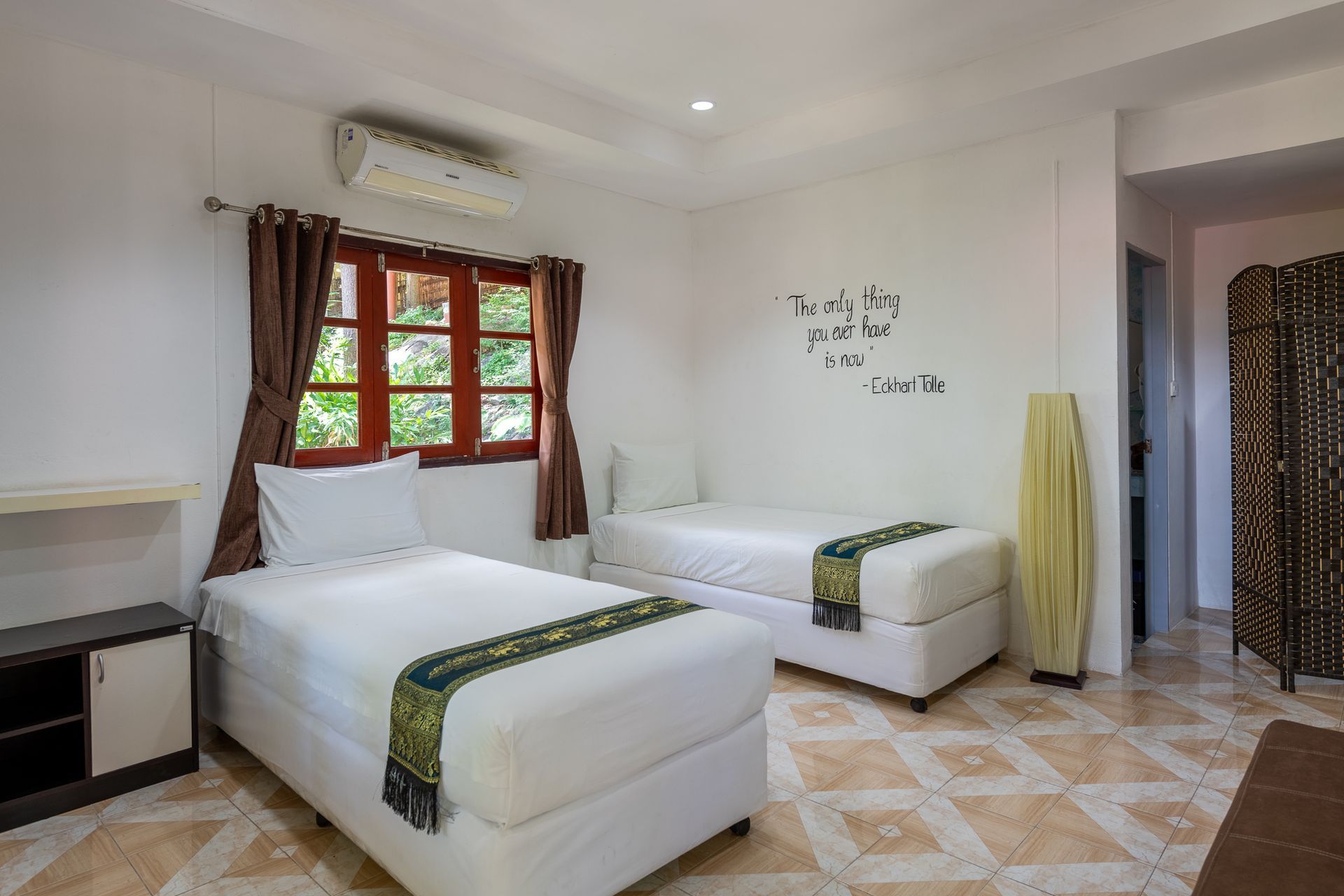 A bright bedroom with two beds, a window, and decorative wall art.