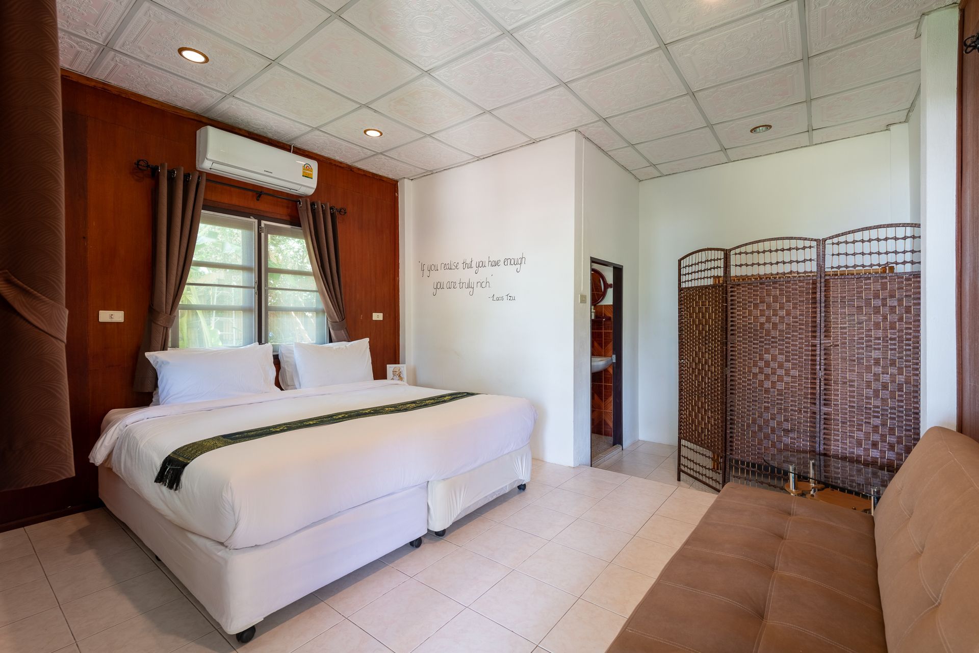 Bedroom with a king bed, window, and sofa, featuring brown and white walls.
