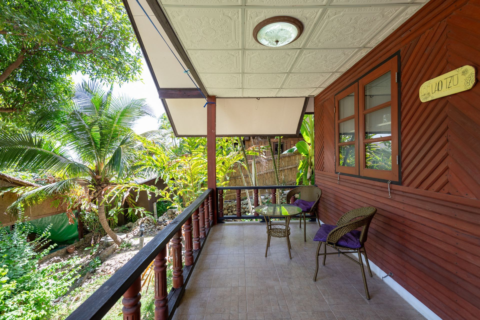 Balcony with wood siding, a table and chairs, and a tropical view.