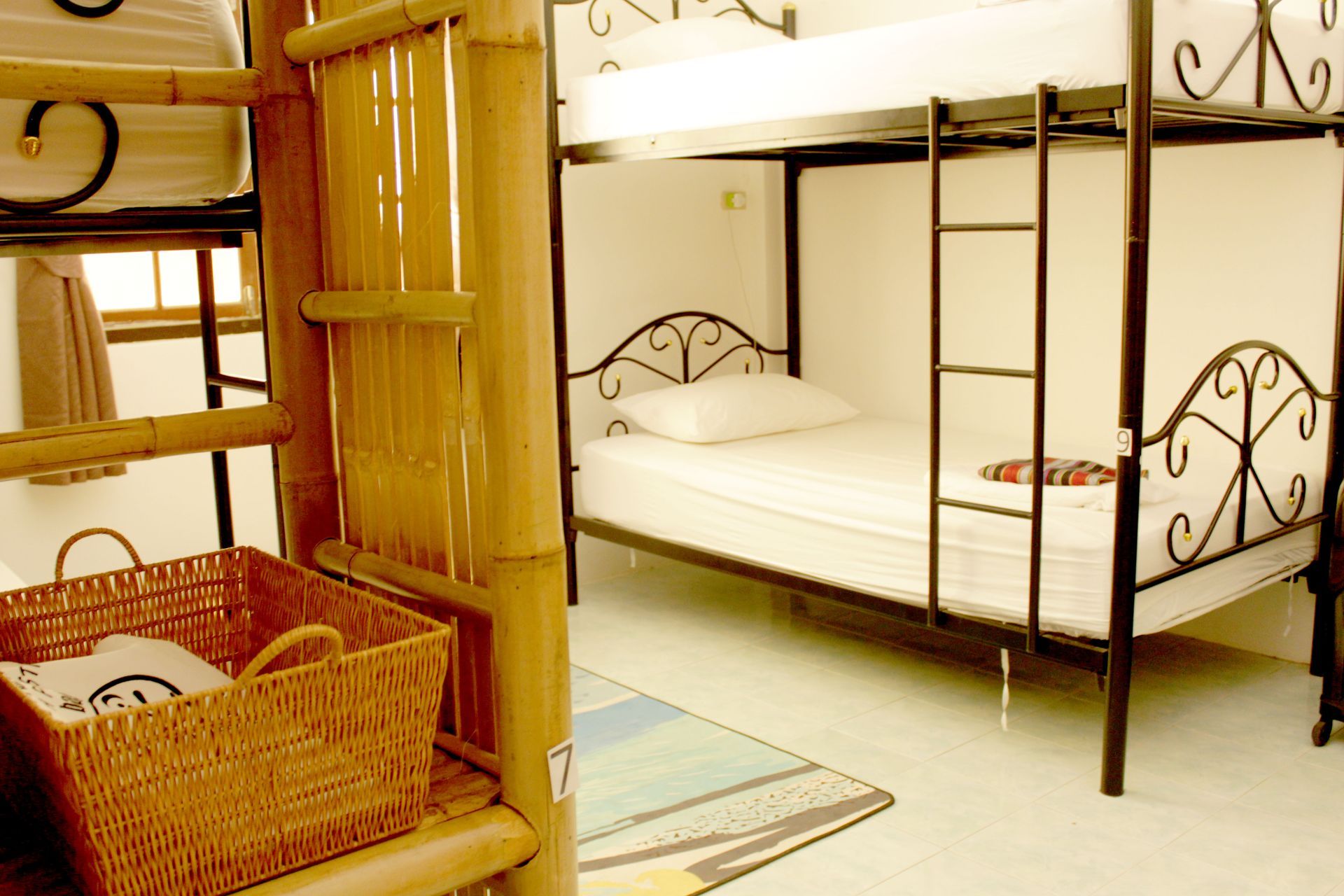 Bunk beds in a hostel room with a wicker basket and bamboo accents.