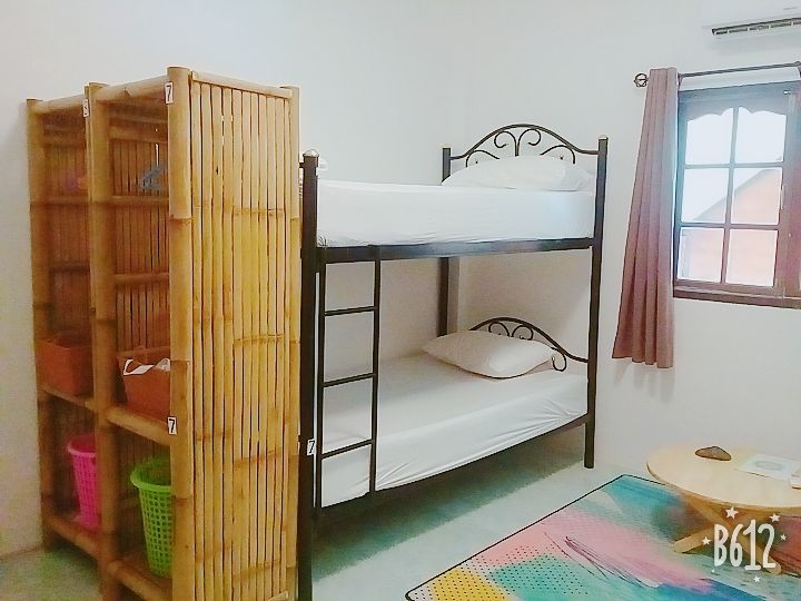 Bunk bed in a room with a bamboo shelf, small table, and a window with pink curtains.