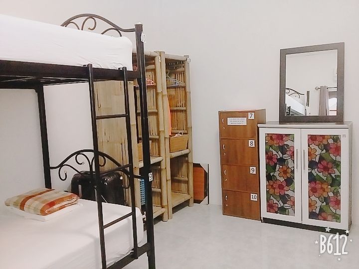 Bunk beds in a room with a shelf, storage cabinets, and a mirror. White walls and floor.