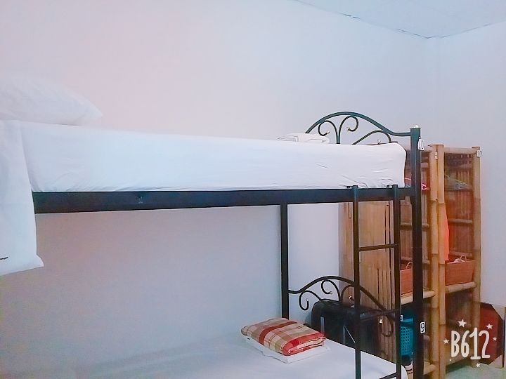 Bunk beds in a room. White sheets and pillows. A wooden shelf and simple decor.