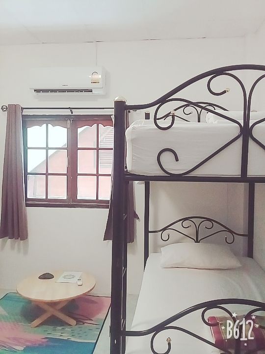 Bunk beds in a white room with a small round table, a window, and an air conditioner.