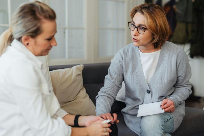 A man is sitting on a couch talking to a woman.