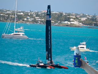 Sailboat with Oracle logo on ocean, held by a person holding a drink.