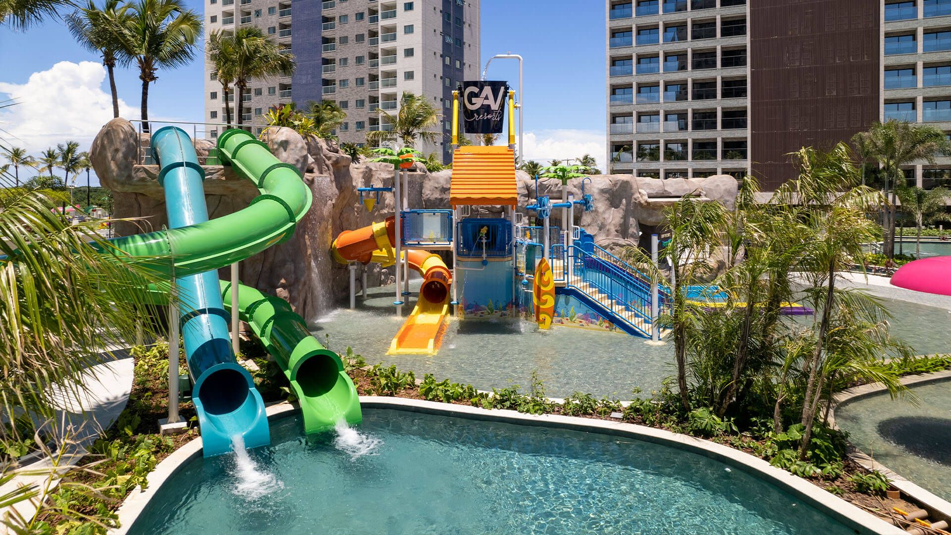 Imagem de uma piscina com um tobogã azul e um verde.