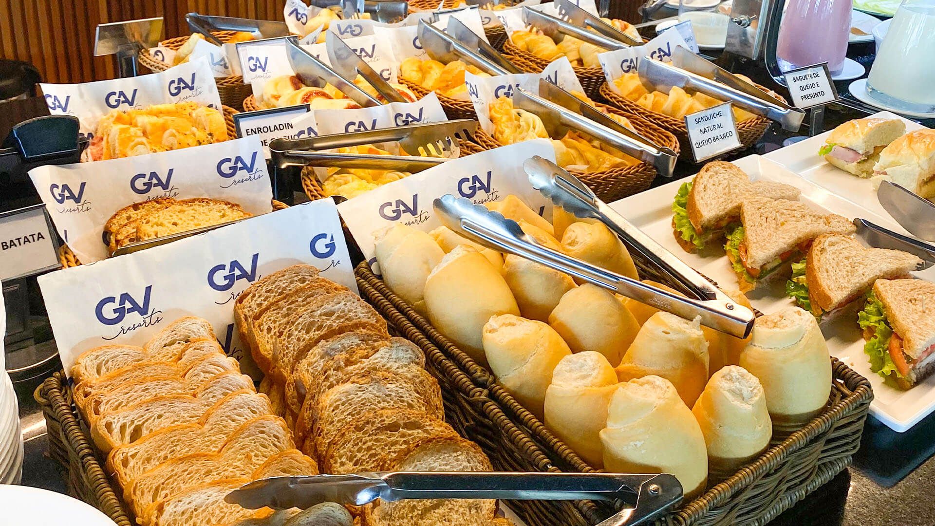 Há muitos tipos diferentes de pães e sanduíches na mesa.