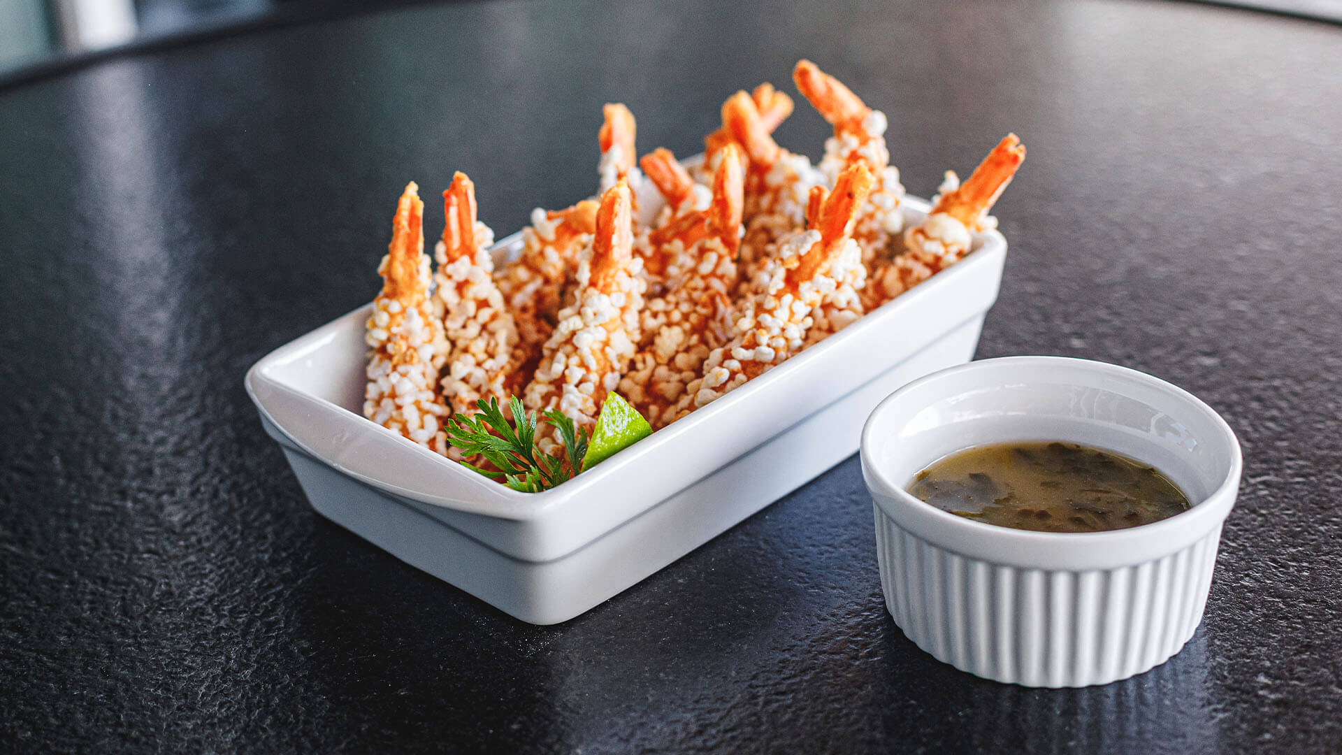 Camarões empanados com molho ao lado.