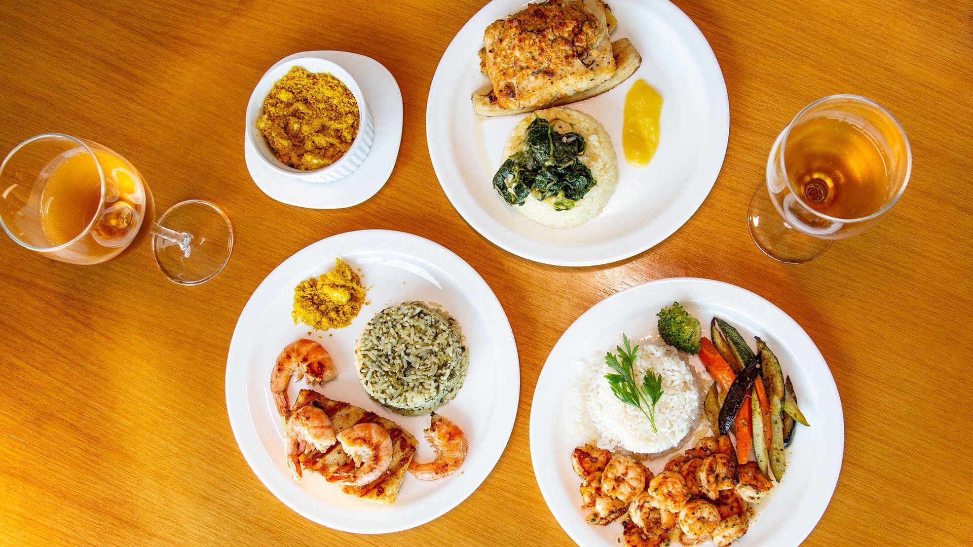 Uma mesa de madeira coberta com pratos de comida e taças de vinho.