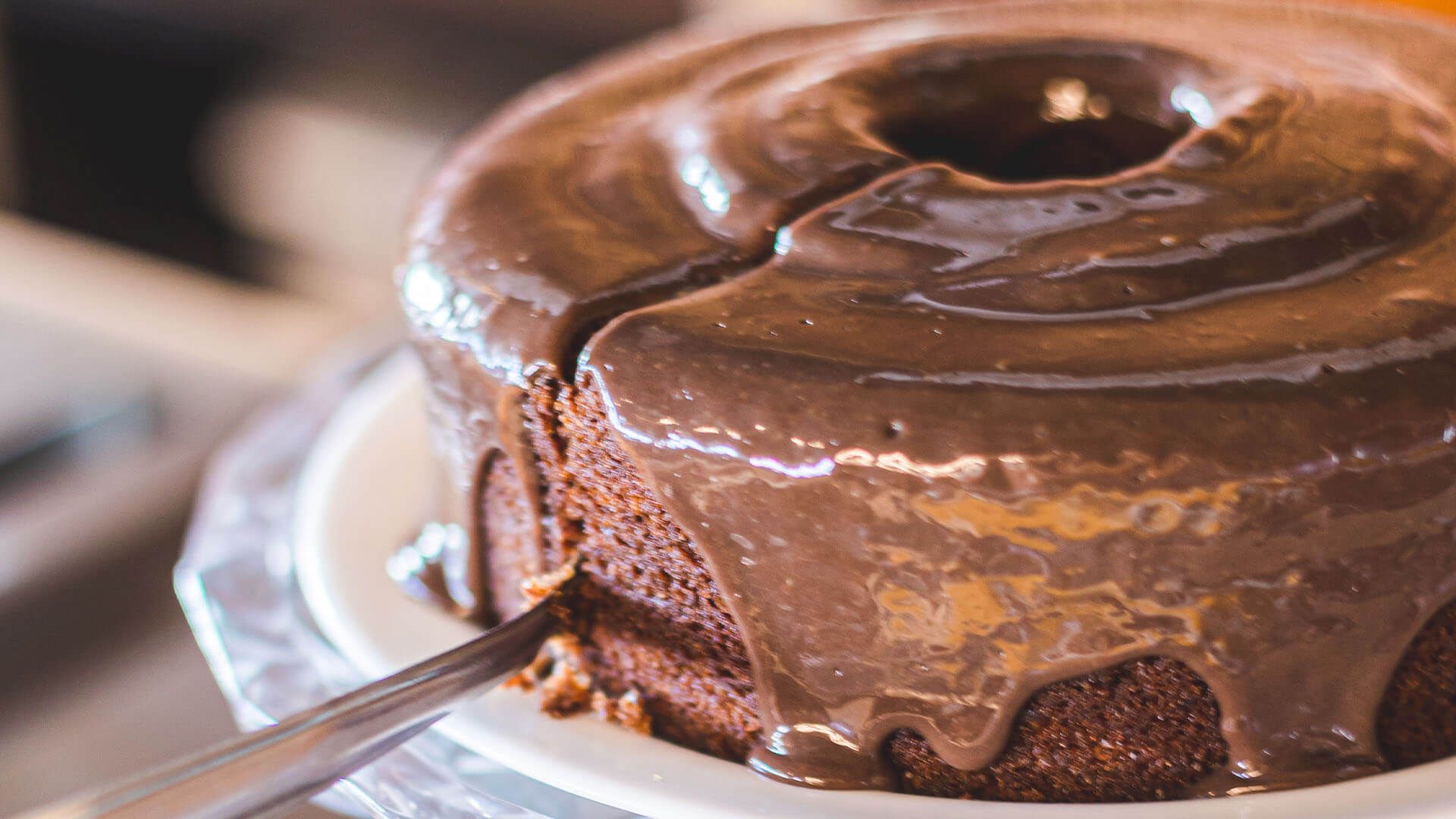 Um close de um bolo de chocolate em um prato com um garfo.