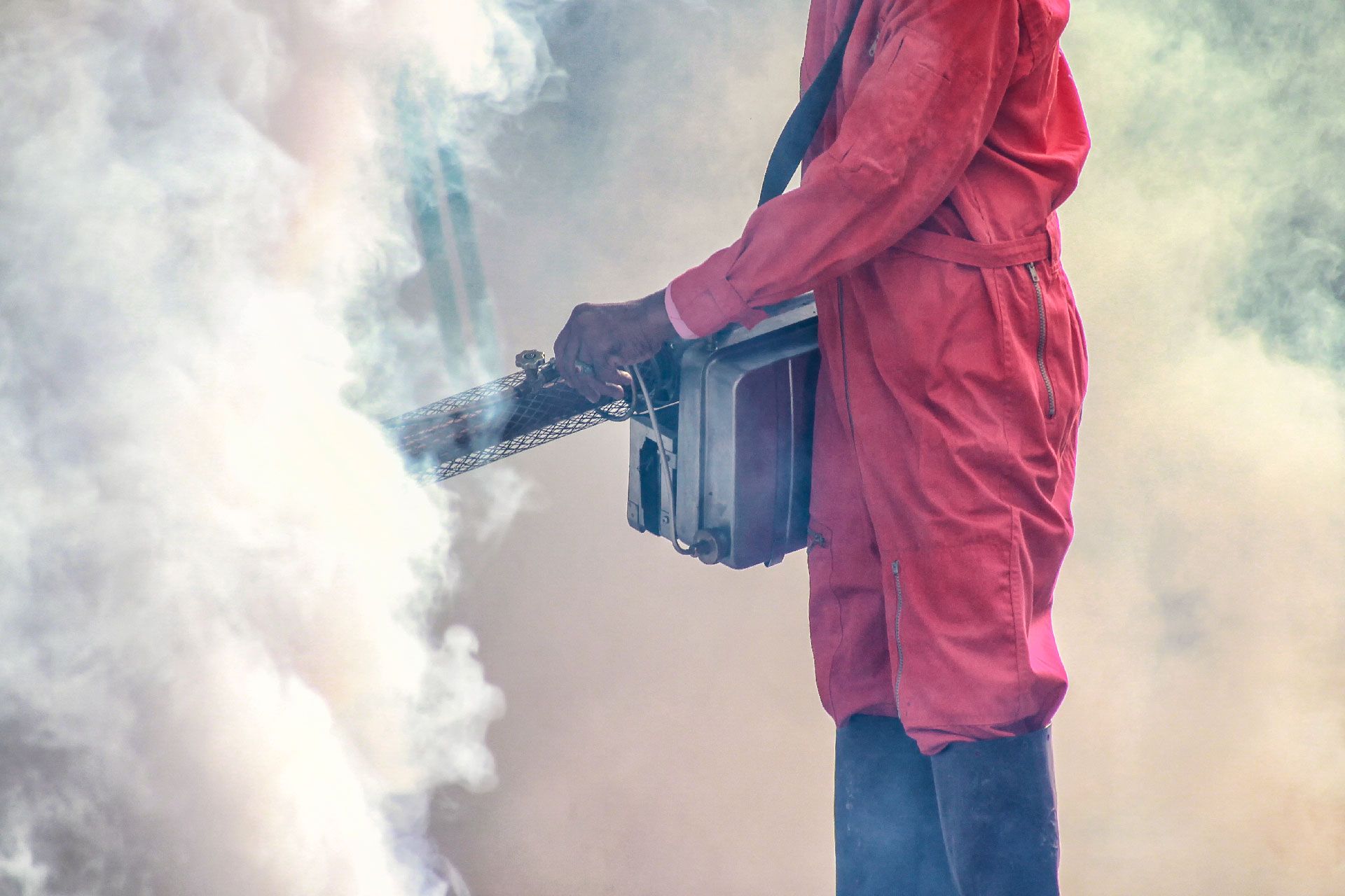 Persona con mono rojo sosteniendo una motosierra, rodeada de humo.