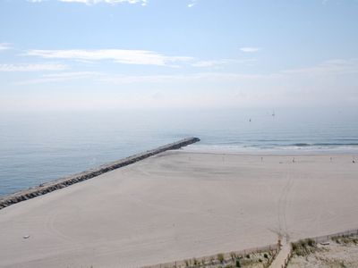 An aerial view of a beach with a pier in the distance.
