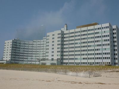 A large building is sitting on top of a sandy beach