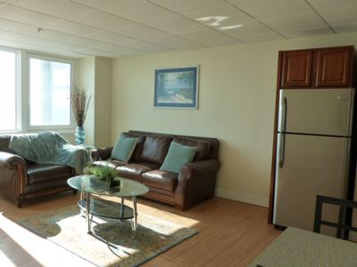 A living room with a couch a coffee table and a refrigerator