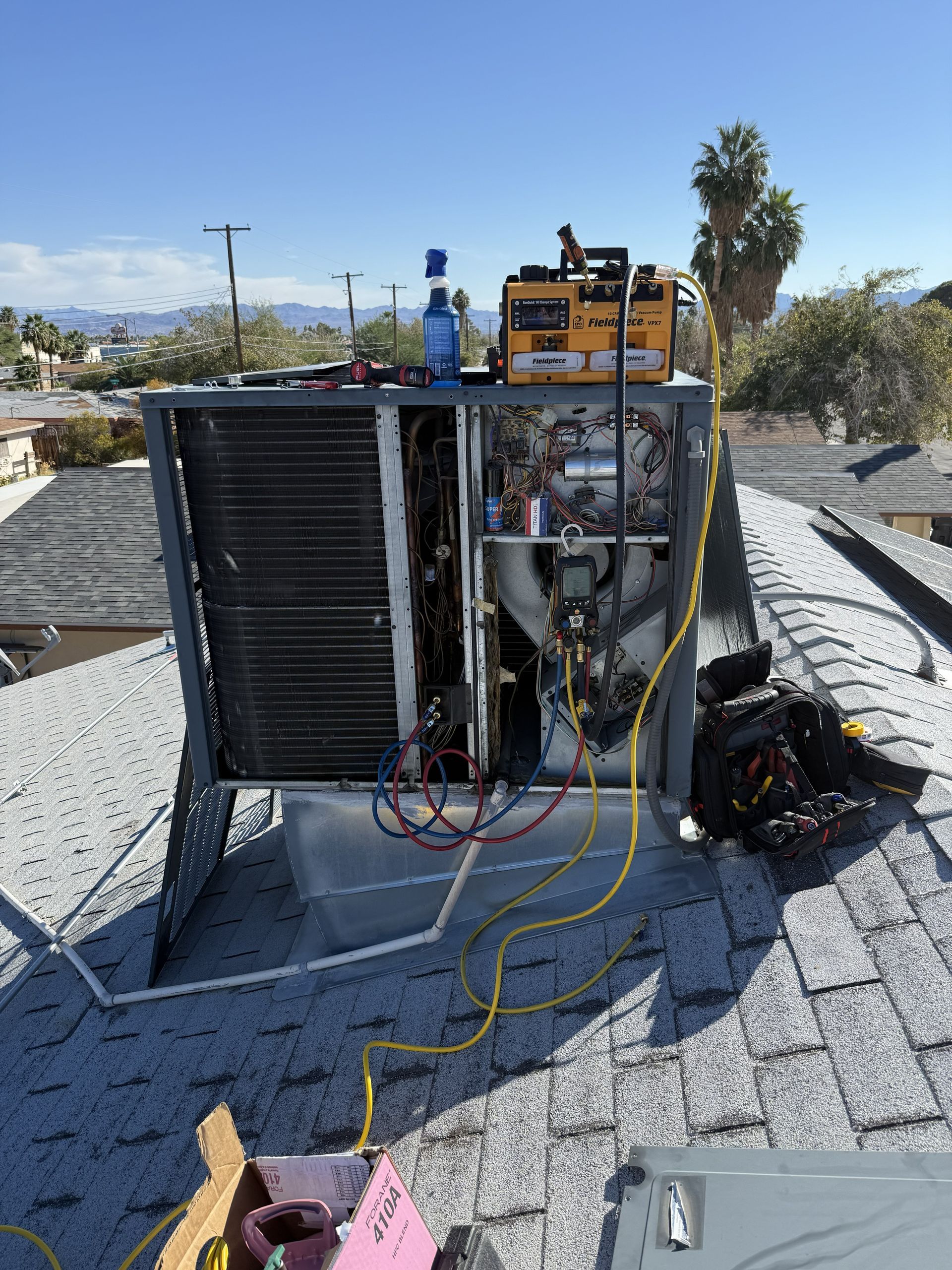 HVAC unit on rooftop being serviced. Equipment and tools are visible. Sunny day.