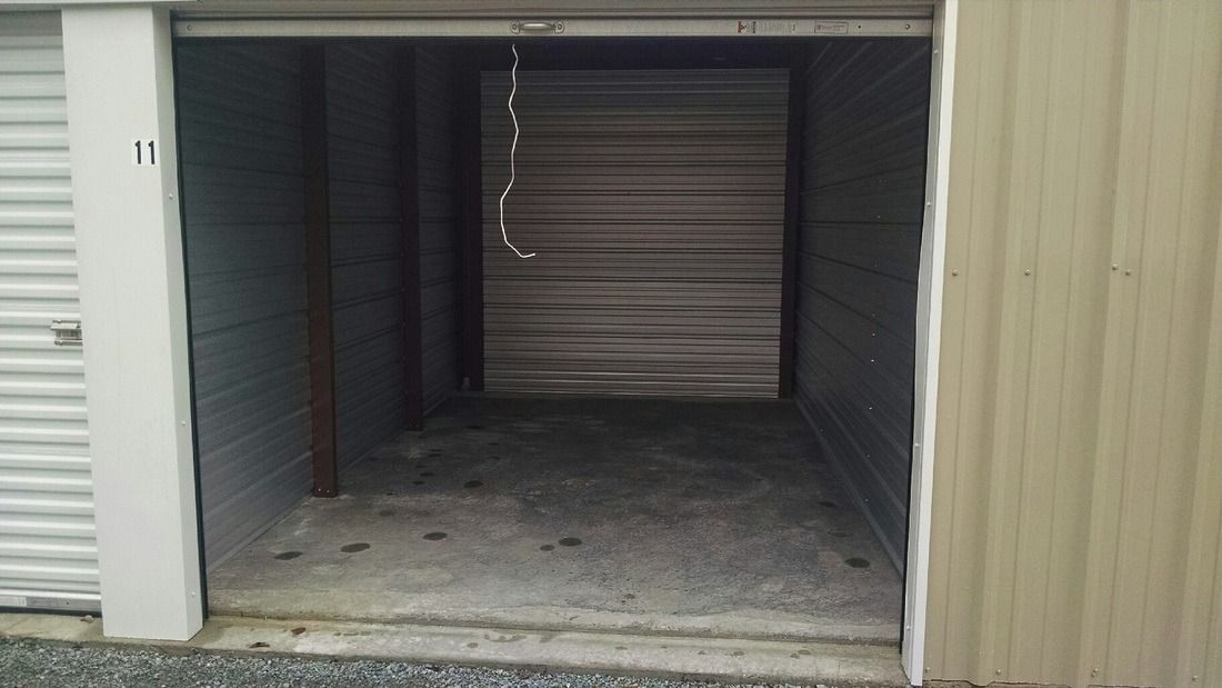Open storage unit, metallic walls, concrete floor, rolling door partially visible at the back.