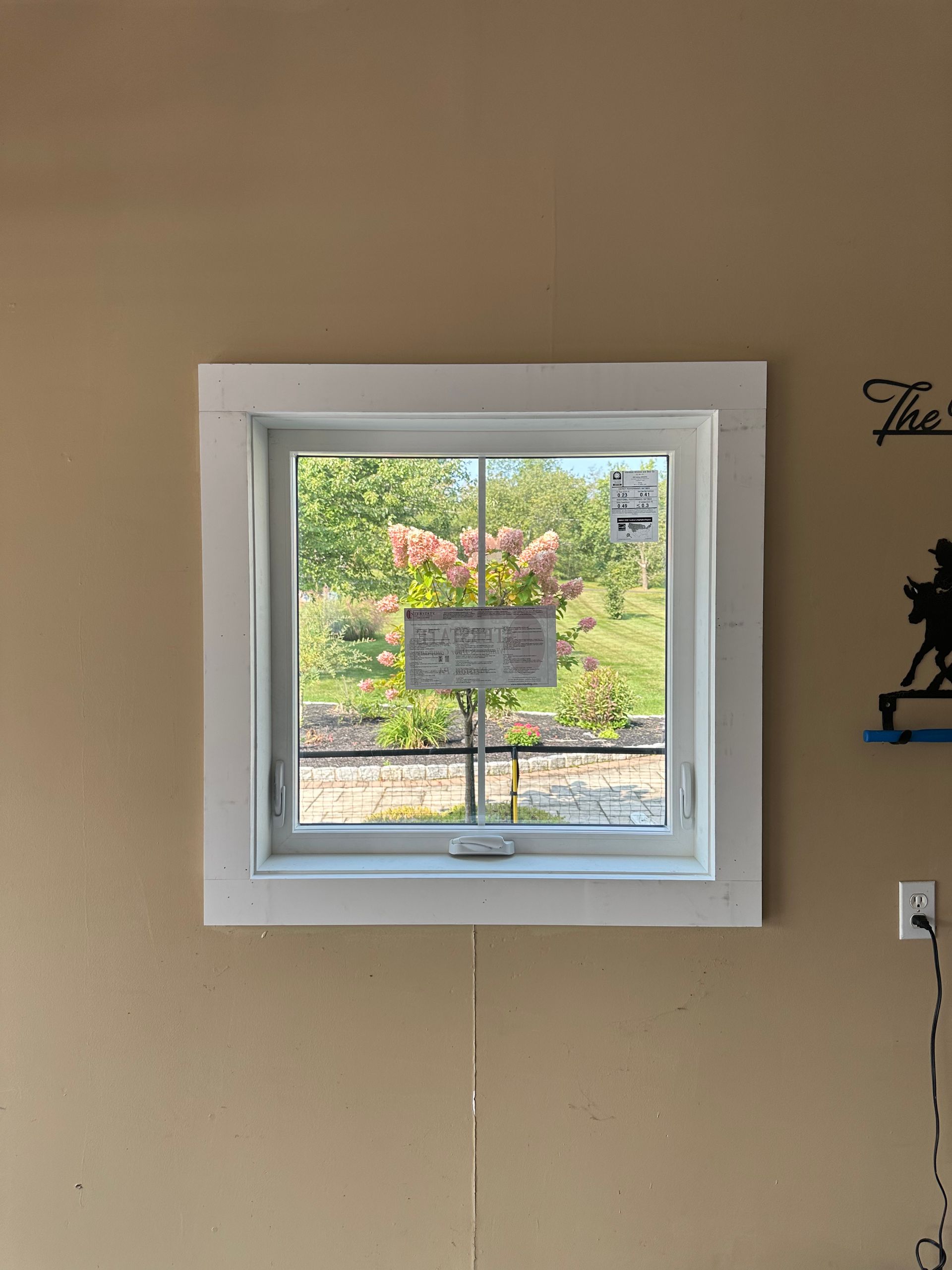 A window with a white frame is hanging on a tan wall.