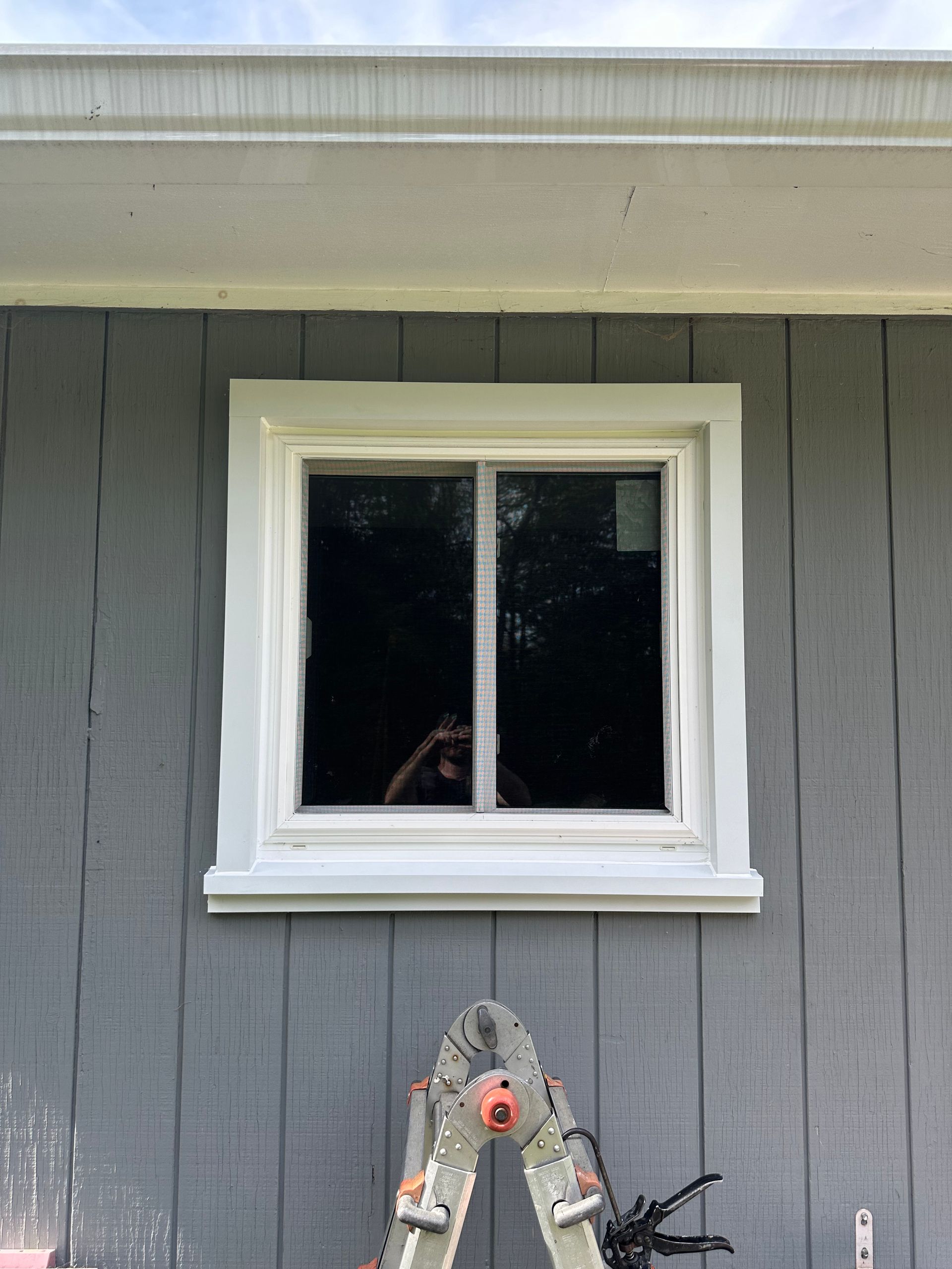 A ladder is sitting next to a window on the side of a house.