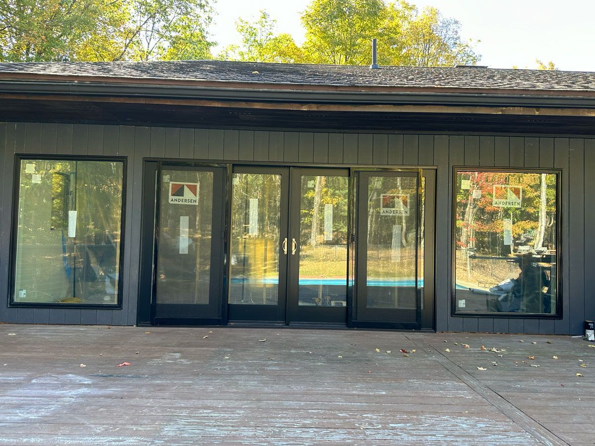 A black house with a lot of windows and sliding glass doors.