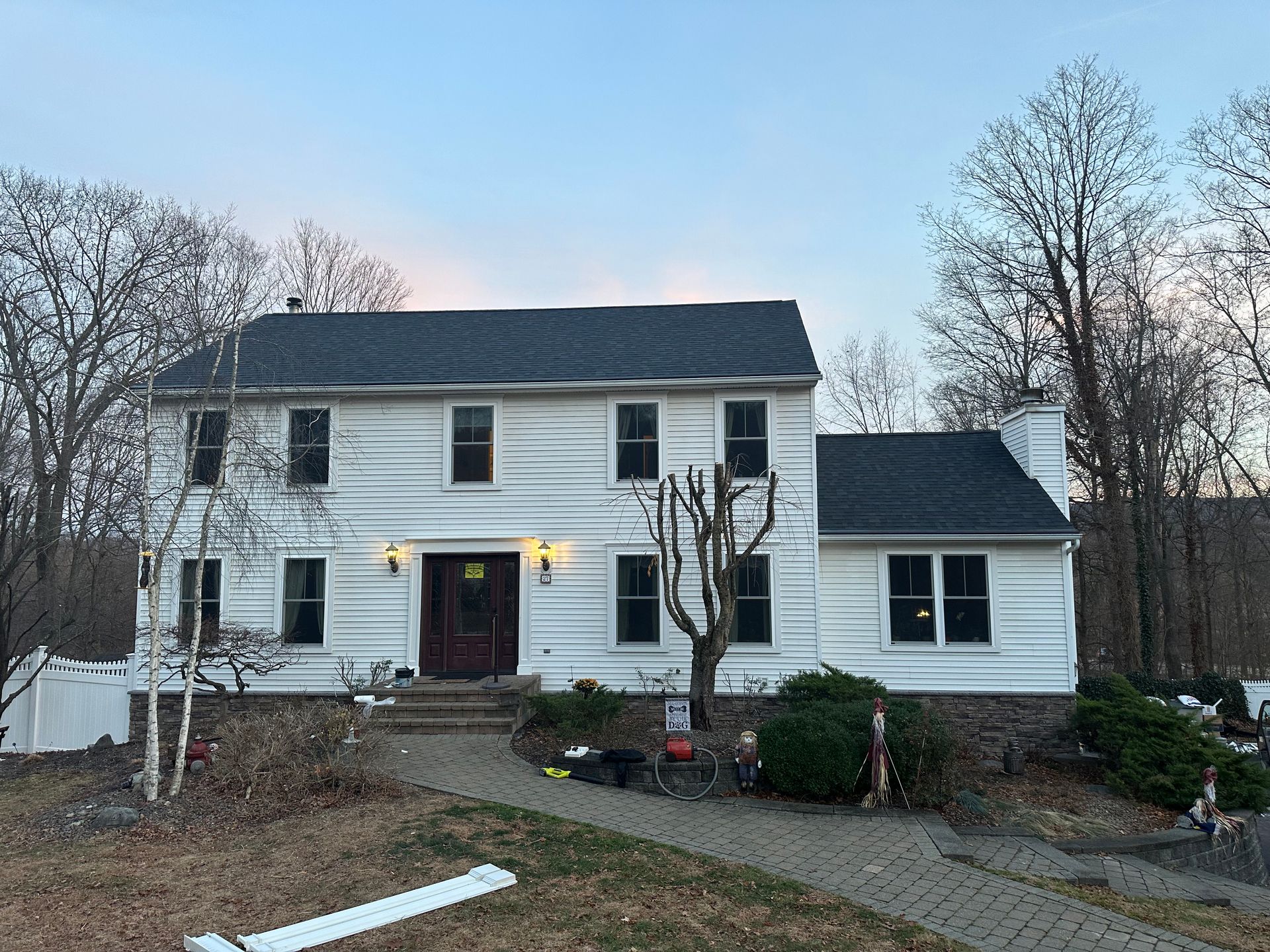 A large white house with a black roof is surrounded by trees.