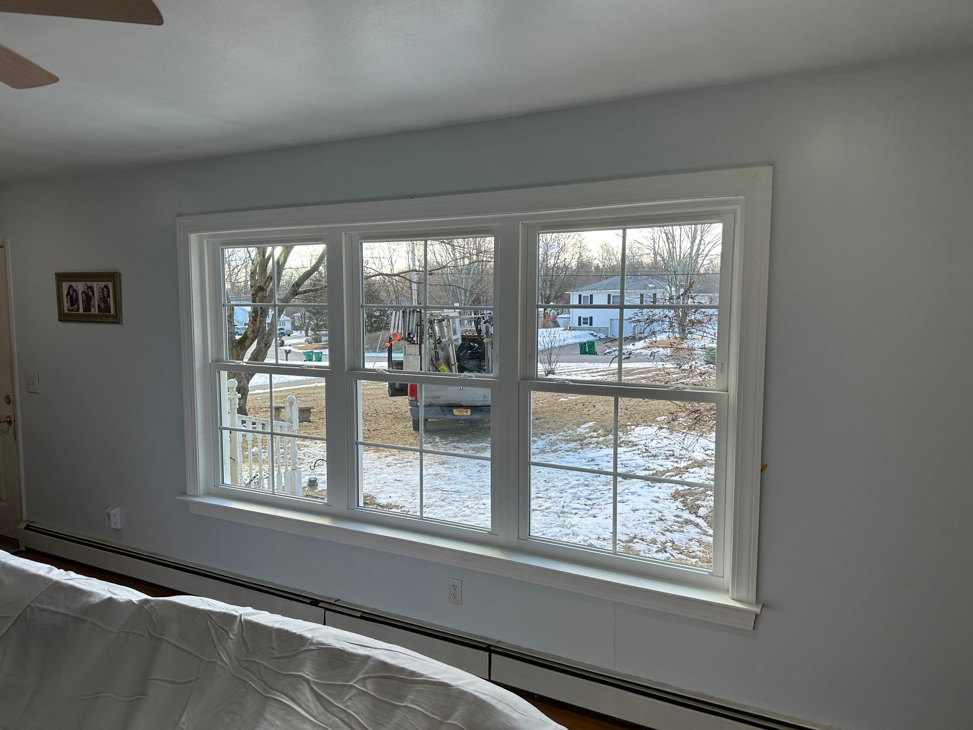 A bedroom with a large window and a ceiling fan.