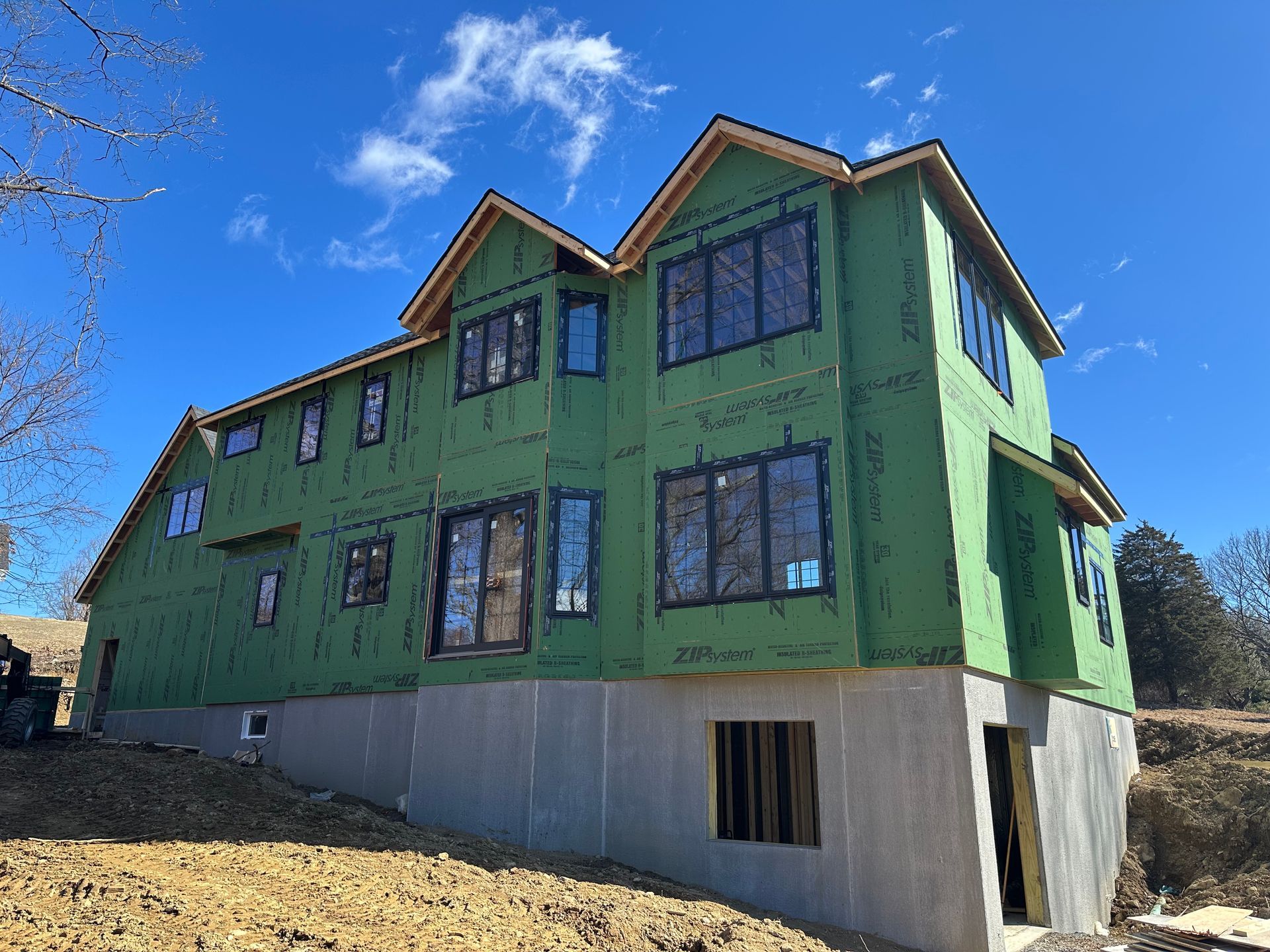 A large house is being built with green insulation and windows.