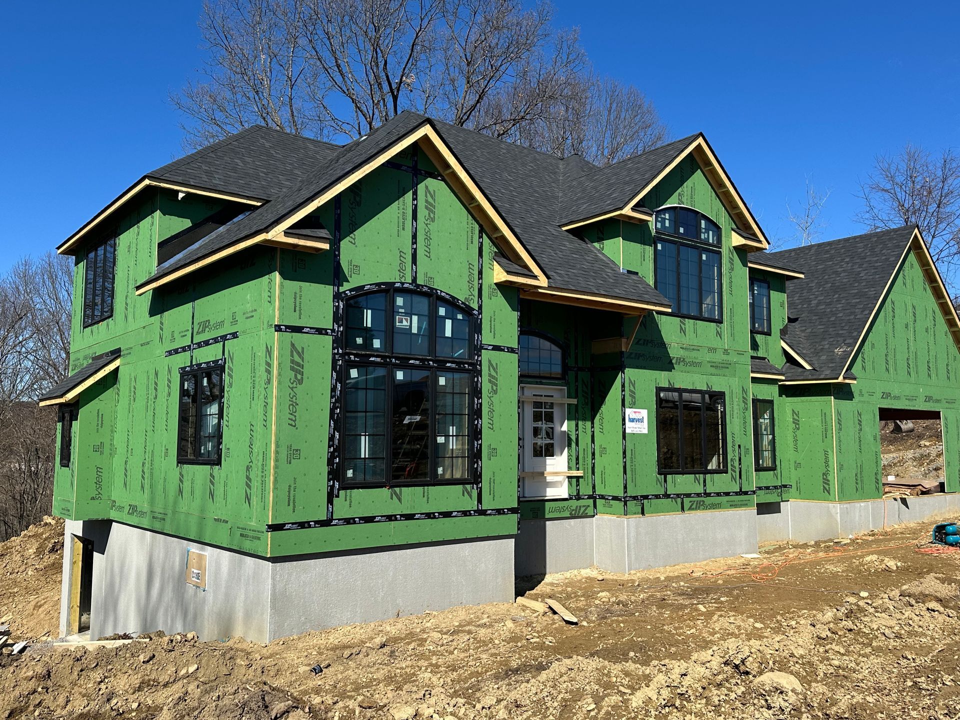 A house is being built with green siding and a black roof.