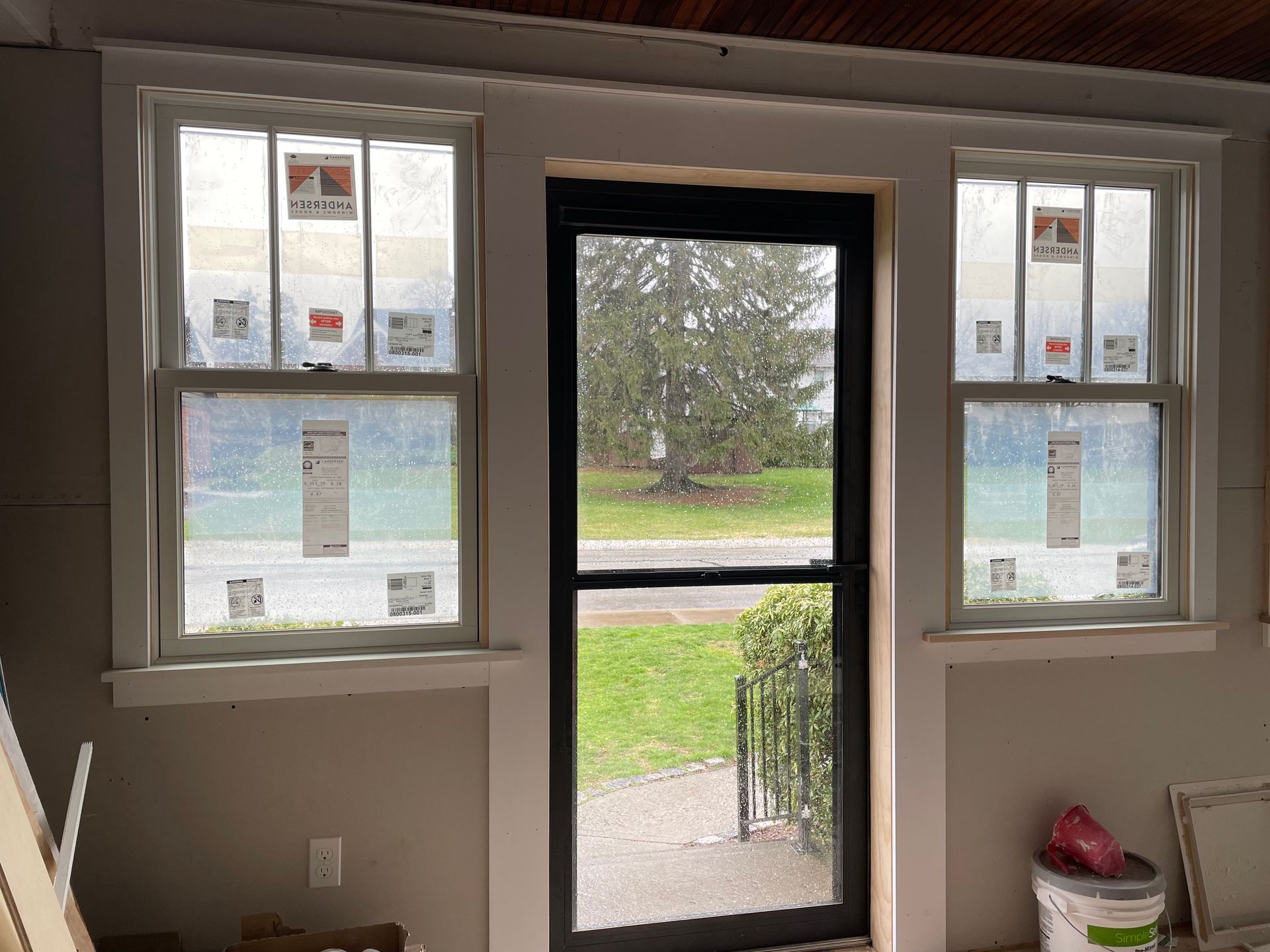 A room with two windows and a black door.