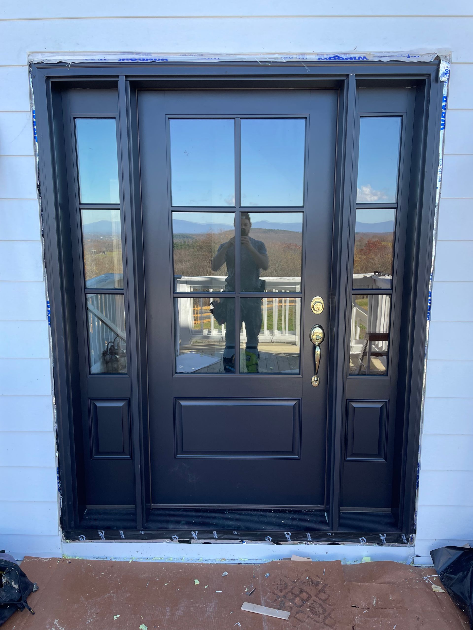 A black door is being installed on a white house.