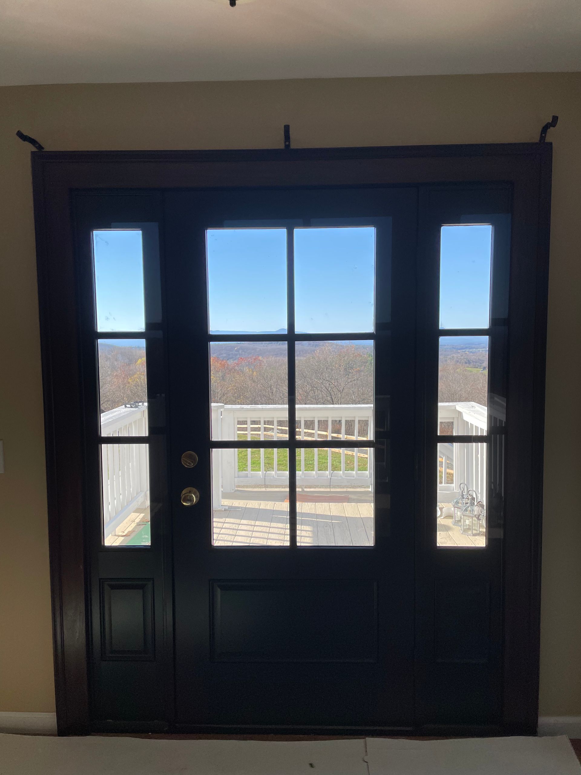 A black door with a view of a balcony.