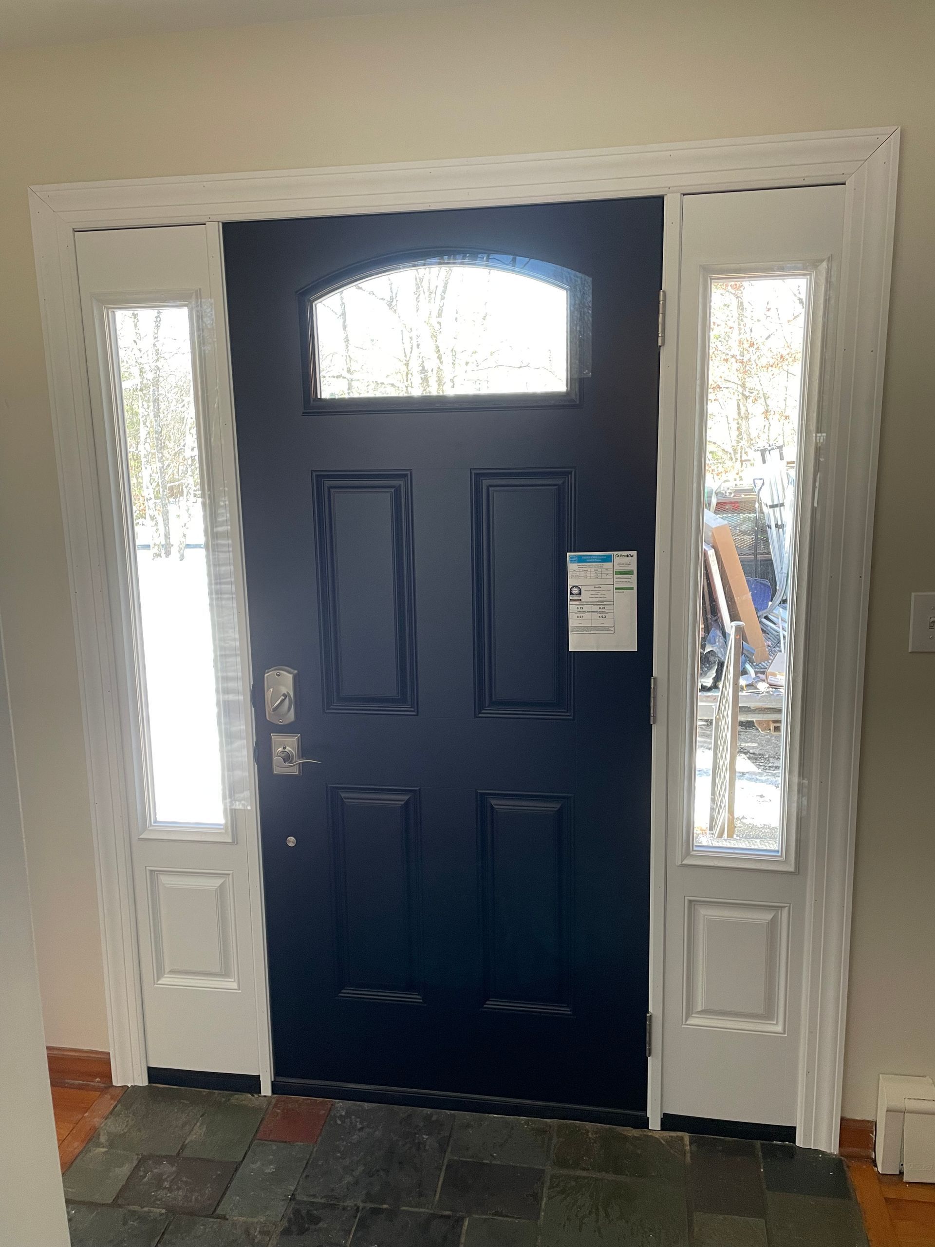 A black door with white trim and windows in a house.