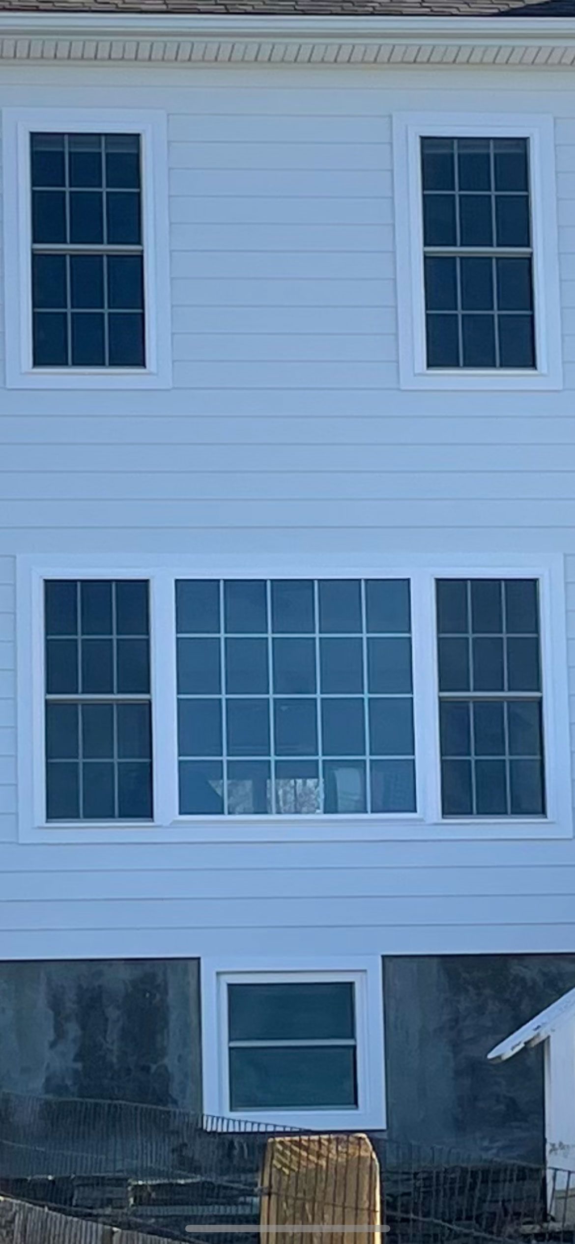 A white house with a lot of windows and a fence in front of it.