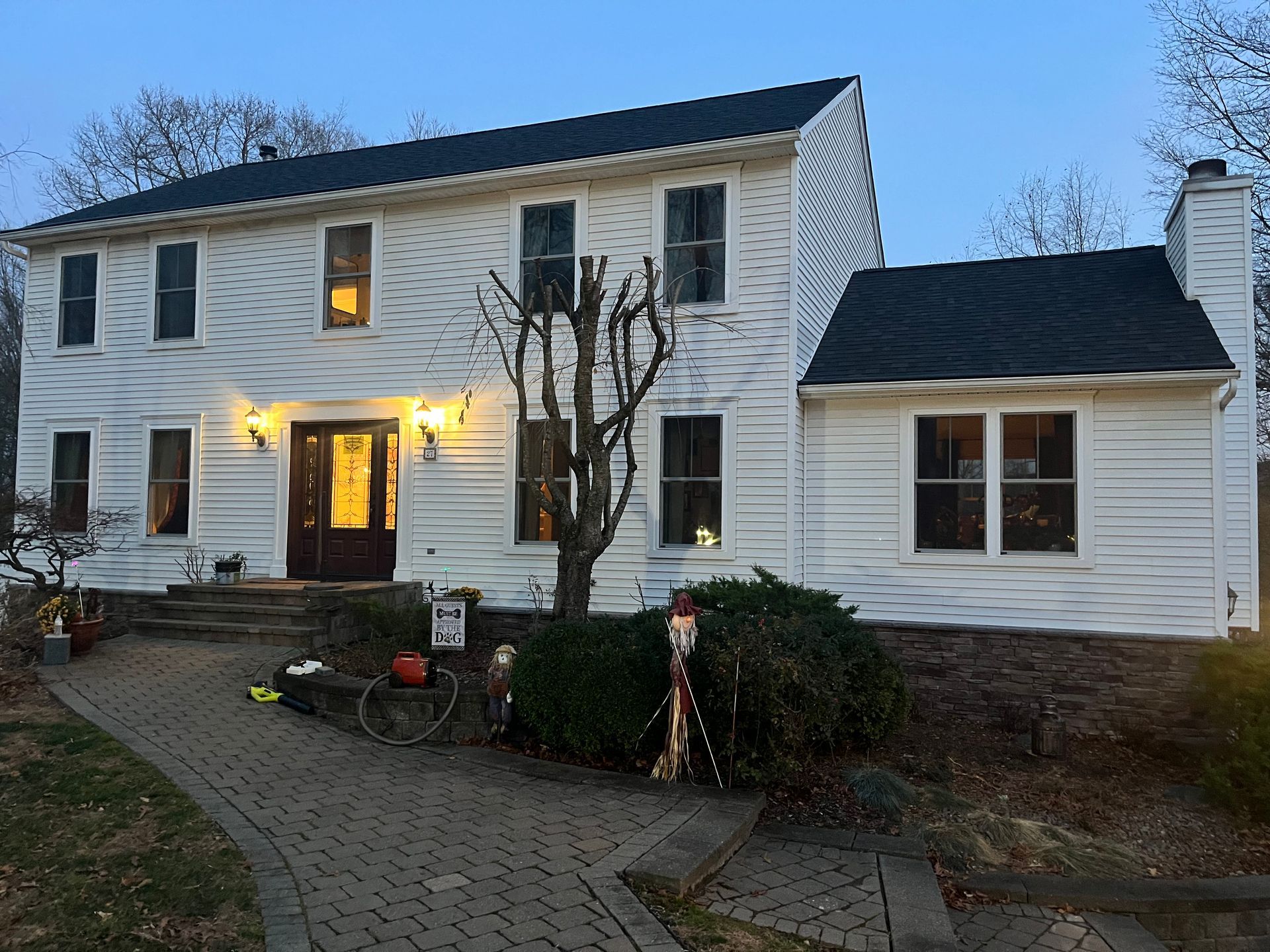 A large white house with a black roof is lit up at night.