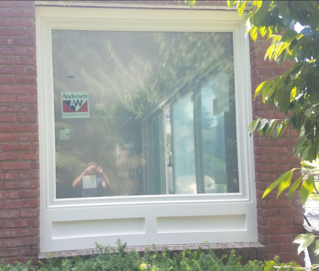 A man is taking a picture of himself in a window of a brick building.