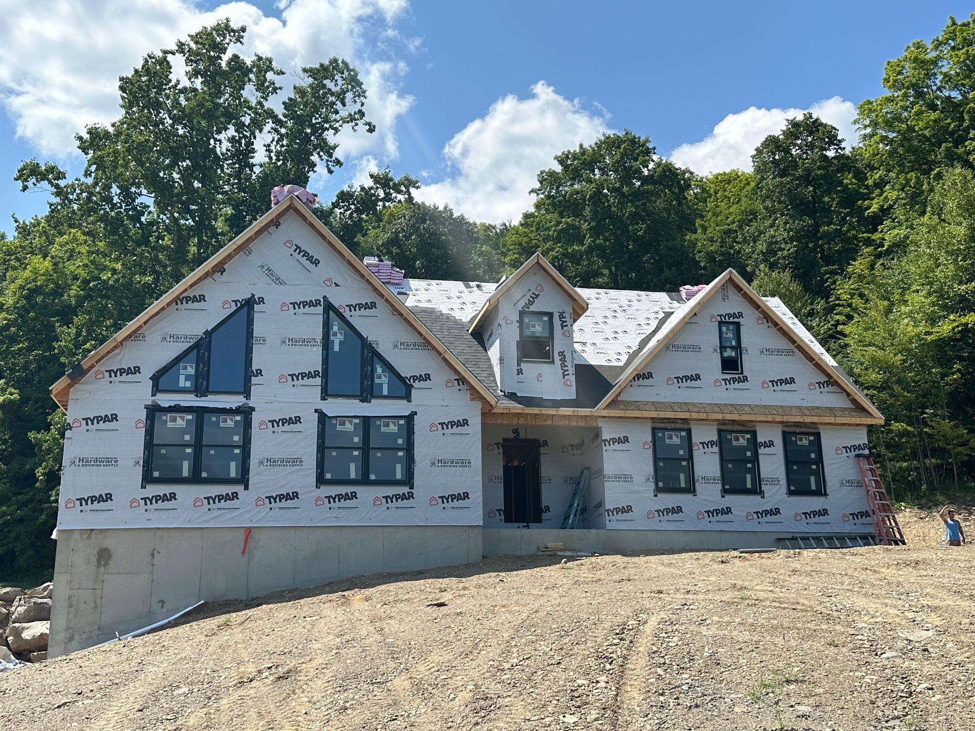 A house is being built on a hill with trees in the background