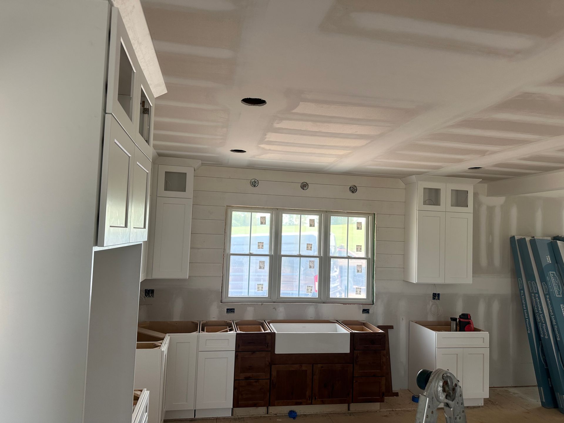 A kitchen under construction with white cabinets and a sink.