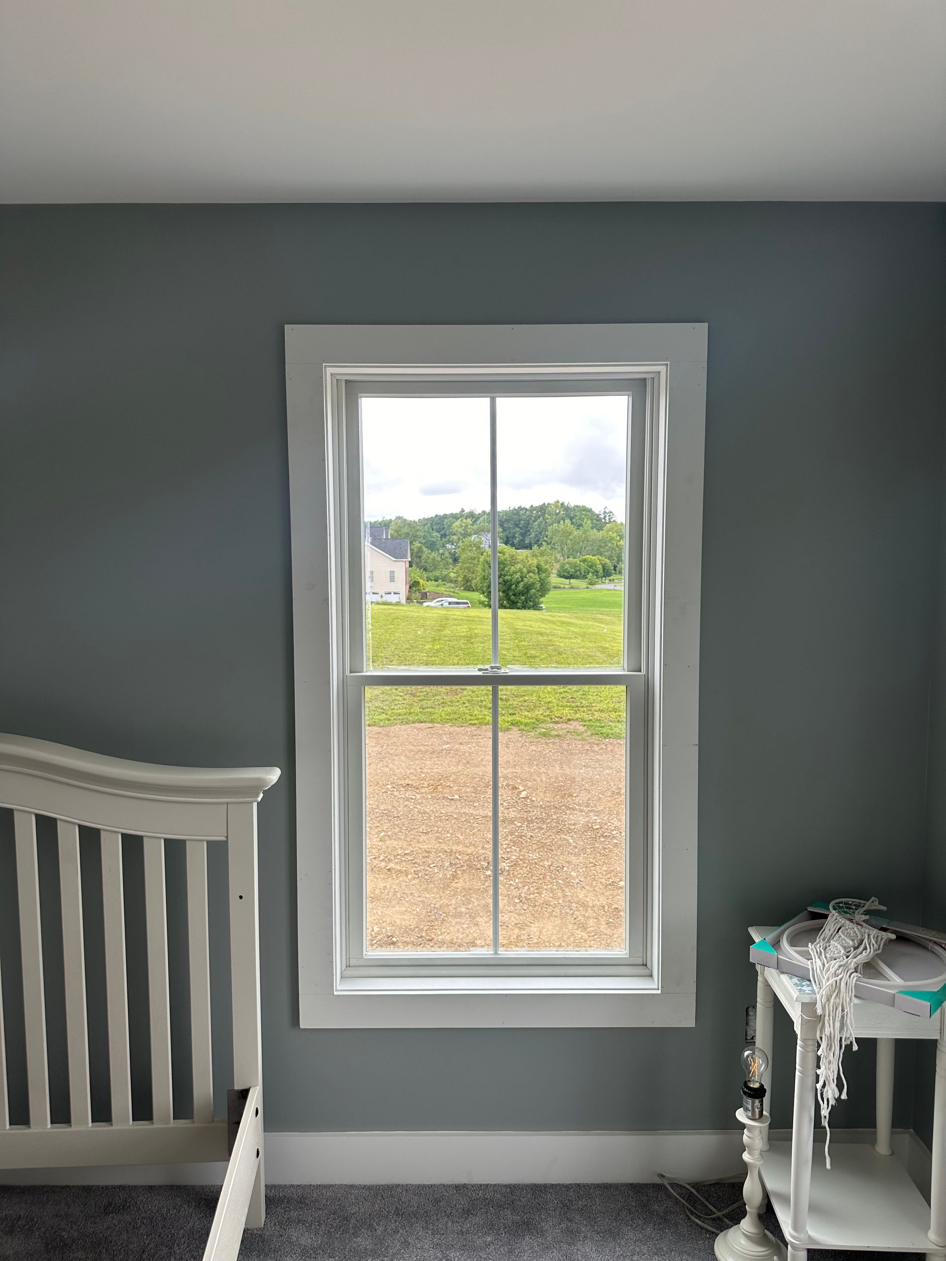A bedroom with a crib and a window with a view of a field