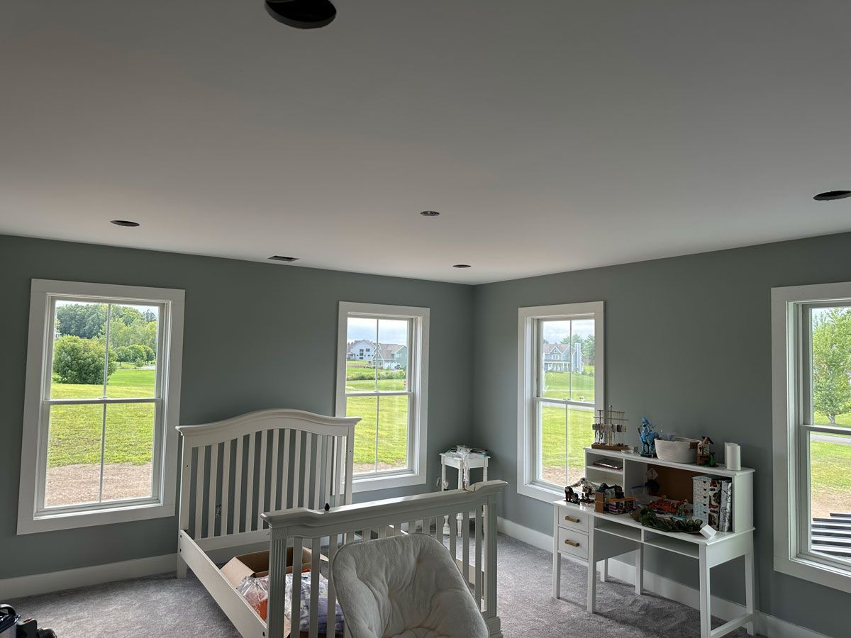 A bedroom with a bed , desk , and lots of windows.