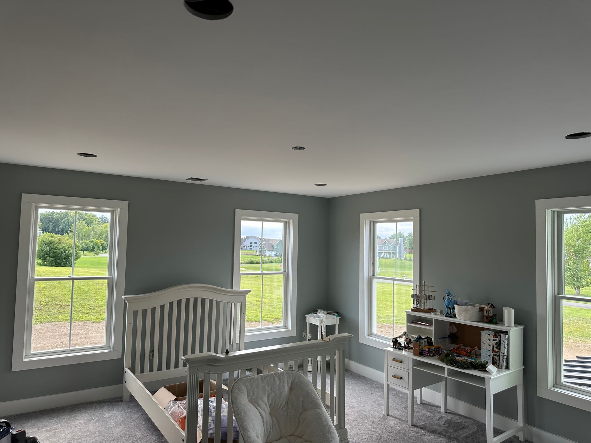 A bedroom with a bed , desk , and lots of windows.