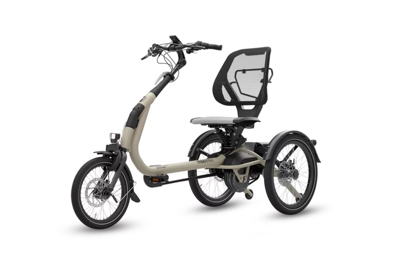 Crèmekleurige driewieler voor volwassenen met een rugleuning van gaas en een koplamp aan de voorzijde, waarschijnlijk voor recreatief of therapeutisch gebruik.