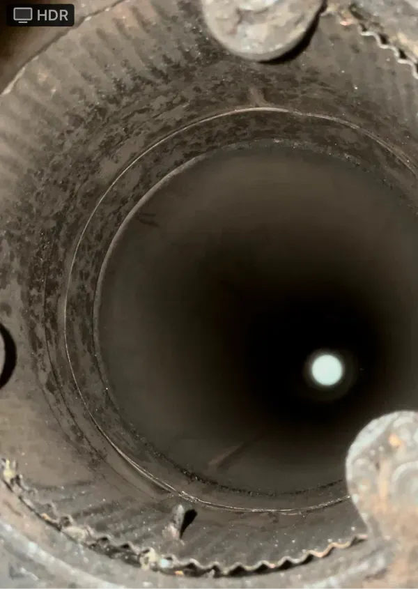 A close up of a hole in a metal pipe with a light coming out of it.